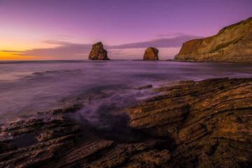 Rocks of Two Sisters of Hendaye with purple and orange sunset sky. France