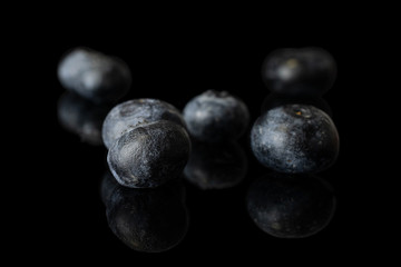 Group of five whole fresh blue blueberry isolated on black glass