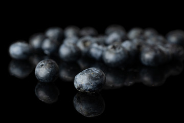 Lot of whole fresh blue blueberry heap isolated on black glass