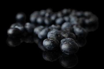 Lot of whole dark fresh blue blueberry heap isolated on black glass