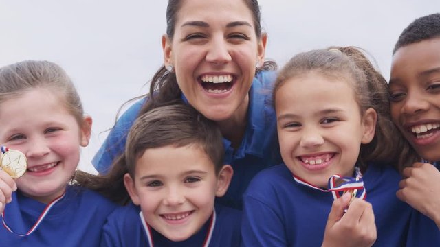 Children With Female Coach Showing Off Winners Medals On Sports Day