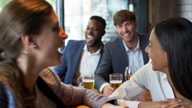 Group Of Business Colleagues Looking At Photos On Mobile Phone In Bar After Work