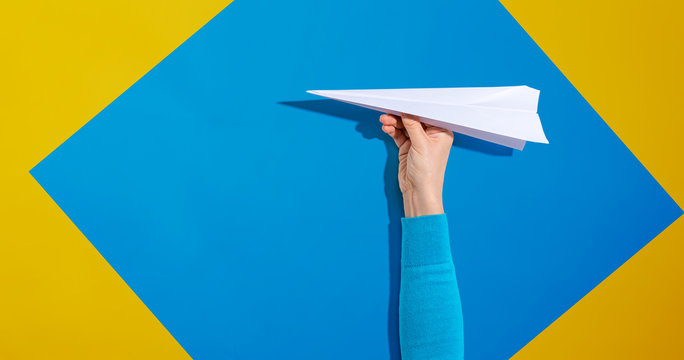 Person Holding A Paper Airplane With Hard Shadow