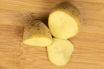 Group of two halves one slice of raw brown potato flatlay on light wood