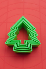 Christmas tree cookie cutters on red baking mat. Plastic Christmas tree on red