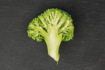 One half of fresh green broccoli flatlay on grey stone