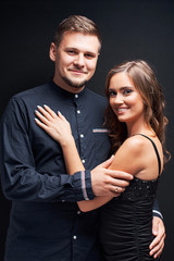 Portrait of young couple in elegant evening clothes isolated on black background.