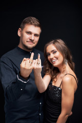 Portrait of young couple in elegant evening clothes showing their wedding rings.