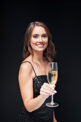 Young happy woman in elegant dress with glass of champagne at party.