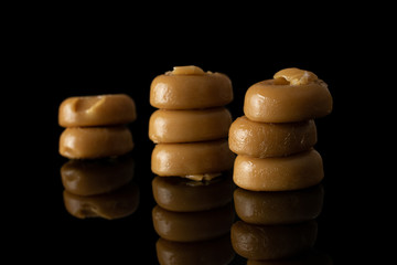 Lot of whole caramel brown candy heap isolated on black glass