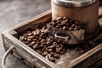 Coffee with coffee grinder and coffee beans on dark textured background.