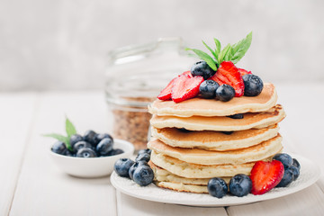 Classic american pancakes with fresh berry on white wood background. Summer homemade breakfast.