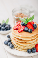 Classic american pancakes with fresh berry on white wood background. Summer homemade breakfast.