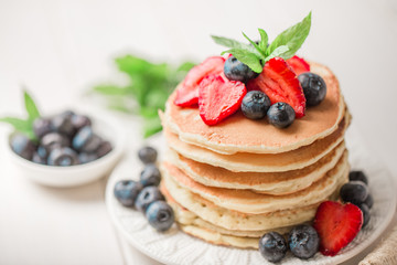 Classic american pancakes with fresh berry on white wood background. Summer homemade breakfast.