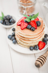 Classic american pancakes with fresh berry on white wood background. Summer homemade breakfast.