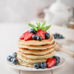Classic american pancakes with fresh berry on white wood background. Summer homemade breakfast.