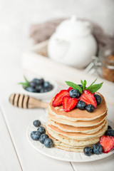 Classic american pancakes with fresh berry on white wood background. Summer homemade breakfast.