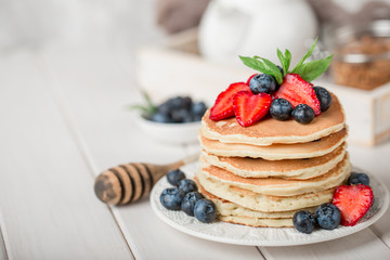 Classic american pancakes with fresh berry on white wood background. Summer homemade breakfast.