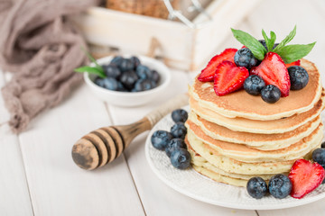 Classic american pancakes with fresh berry on white wood background. Summer homemade breakfast.