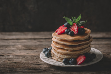 American pancakes with fresh berry on wood background. Summer homemade breakfast.