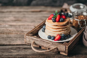 American pancakes with fresh berry on wood background. Summer homemade breakfast.