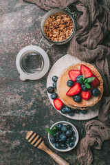 American pancakes with fresh berry and granola on metal background. Summer homemade breakfast.