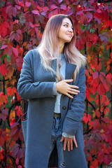 Dreamy beautiful girl with long colorful hair on autumn background of red grape hedge. Inspired...