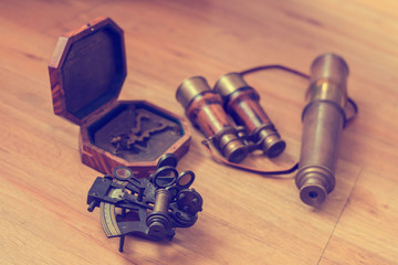 Vintage navigation equipment on wood background. Old Brass Theodolite, Wood pocket compass with cover lid, Old binoculars, old brass telescope, Traveling concept and vintage style.