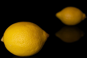 Group of two whole fresh yellow lemon isolated on black glass