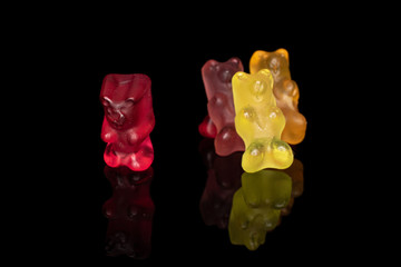 Group of four whole gummy bear isolated on black glass