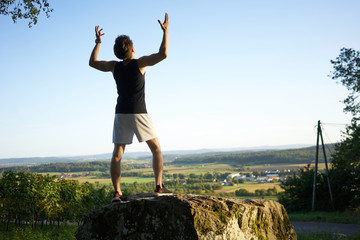sportsman on a rock with arms up in front of view
