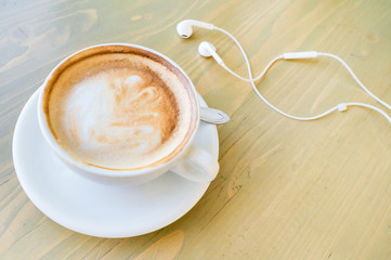 cup of coffee, cappuccino, white top view, headphones for music next to the cup, copy space. selective focus  