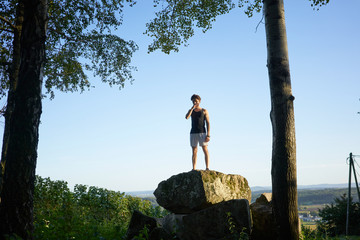 Naklejka na ściany i meble sporty man on a rock in front of blue sky 