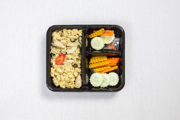Green Curry Chicken Rice put in black plastic box, put on a white tablecloth, food box, Thai food.