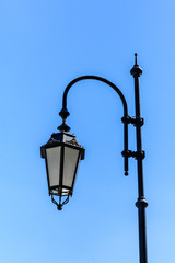Fototapeta na wymiar Old lantern on a metal post against blue sky