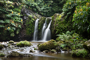 Natural waterfall surrounded by rocks and foliage at the Parque Natural da Ribeira dos Caldeirões,...