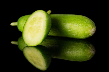 Group of one whole one piece of mini green cucumber isolated on black glass