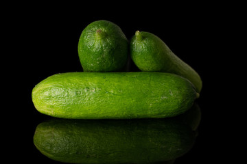 Group of three whole mini green cucumber isolated on black glass