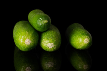 Group of four whole mini green cucumber isolated on black glass