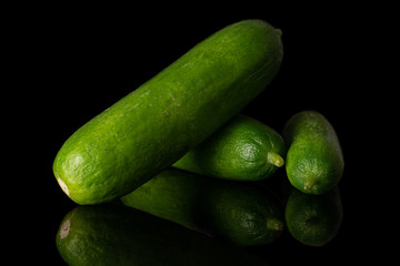 Group of three whole mini green cucumber isolated on black glass