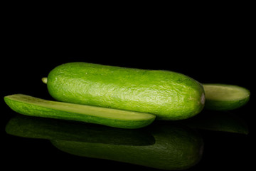 Group of one whole two pieces of mini green cucumber isolated on black glass