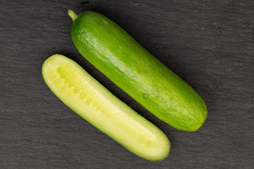 Group of two halves of mini green cucumber flatlay on grey stone