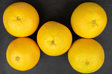 Group of five whole fresh bright orange flatlay on grey stone