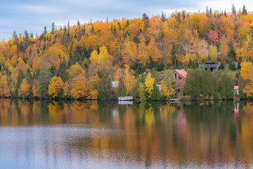 Cottage in the forest on the lake in Canada, during the Indian summer, beautiful colors of the trees 
