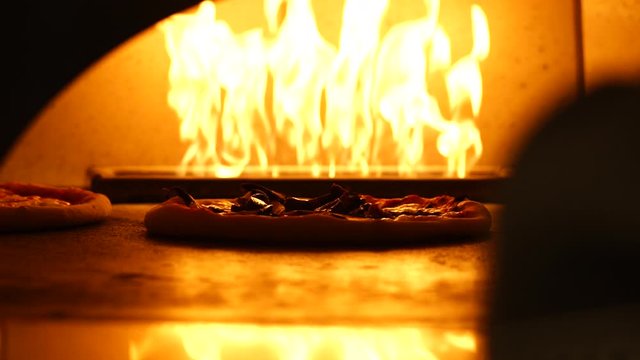 Chef is turning and organizing pizzas in the oven in slow motion