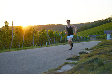 Obraz premium jogger in green vineyard at sunset 
