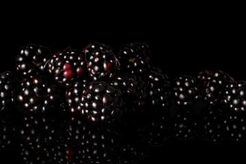 Lot of whole arranged fresh black blackberry isolated on black glass
