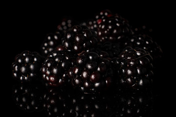 Lot of whole heap fresh black blackberry isolated on black glass