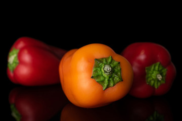 Group of three whole fresh pepper front focus isolated on black glass