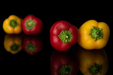 Group of four whole fresh pepper isolated on black glass